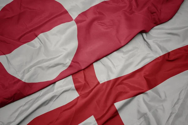 waving colorful flag of england and national flag of greenland.