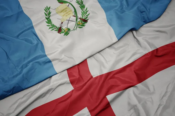 waving colorful flag of england and national flag of guatemala.