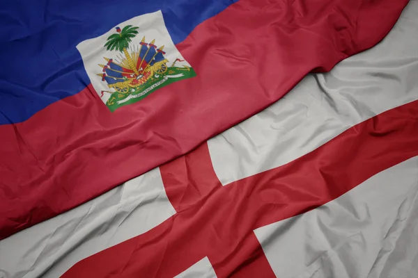 waving colorful flag of england and national flag of haiti.