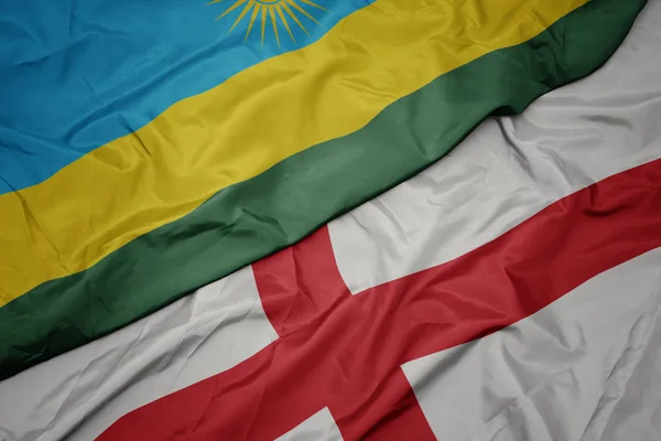 waving colorful flag of england and national flag of rwanda.