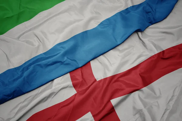 waving colorful flag of england and national flag of sierra leone.