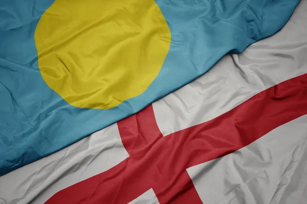 waving colorful flag of england and national flag of Palau .