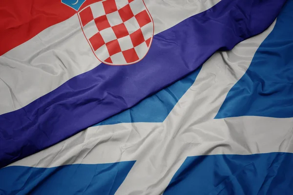 waving colorful flag of scotland and national flag of croatia.