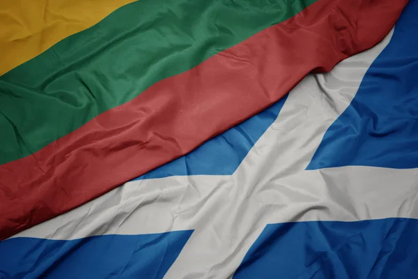 waving colorful flag of scotland and national flag of lithuania.