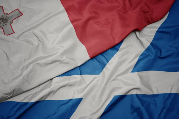 waving colorful flag of scotland and national flag of malta.