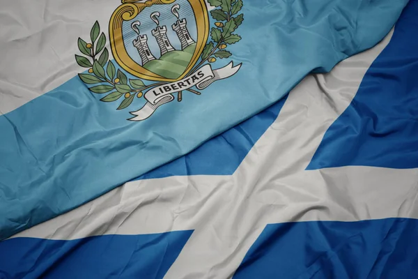 waving colorful flag of scotland and national flag of san marino.