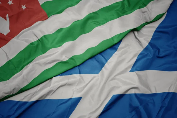Waving colorful flag of scotland and national flag of abkhazia. — Stock Photo, Image