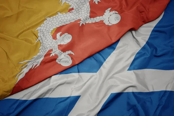 waving colorful flag of scotland and national flag of bhutan.