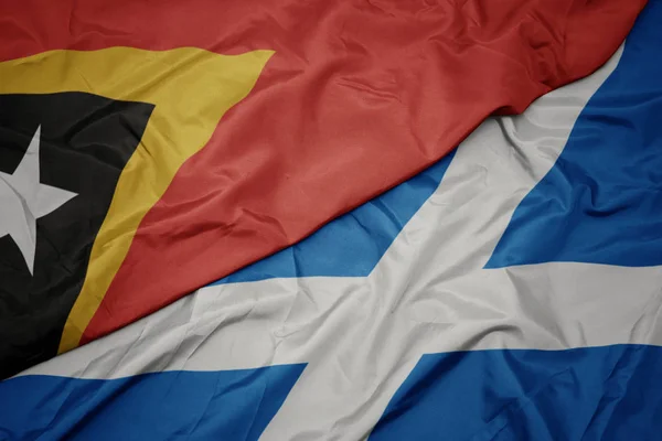 waving colorful flag of scotland and national flag of east timor.