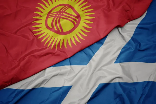waving colorful flag of scotland and national flag of kyrgyzstan.