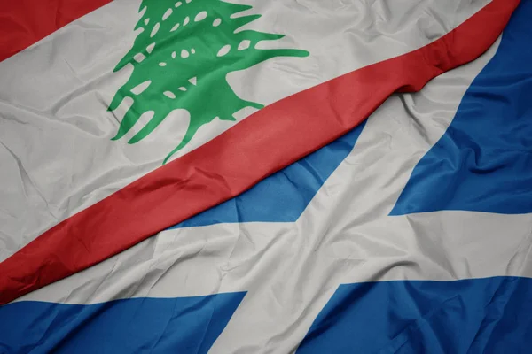 waving colorful flag of scotland and national flag of lebanon.