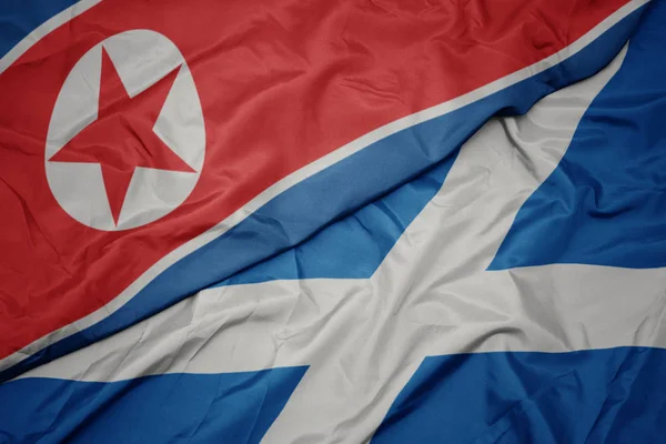 Ondeando colorida bandera de Escocia y bandera nacional de Corea del Norte . —  Fotos de Stock