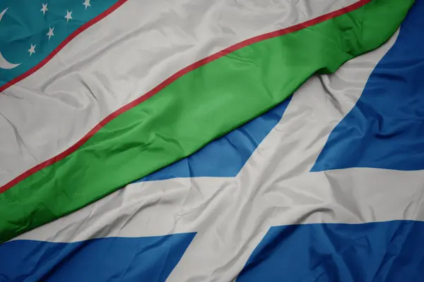 Acenando bandeira colorida da Escócia e bandeira nacional do uzbequistão . — Fotografia de Stock
