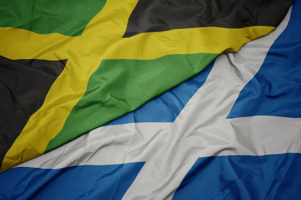 waving colorful flag of scotland and national flag of jamaica.