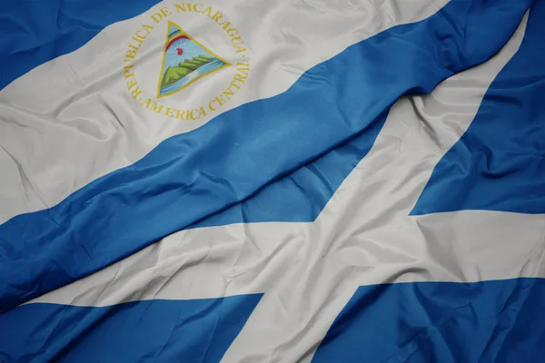 waving colorful flag of scotland and national flag of nicaragua.