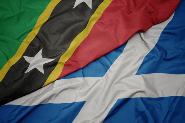 Acenando bandeira colorida da Escócia e bandeira nacional de saint kitts e nevis . — Fotografia de Stock