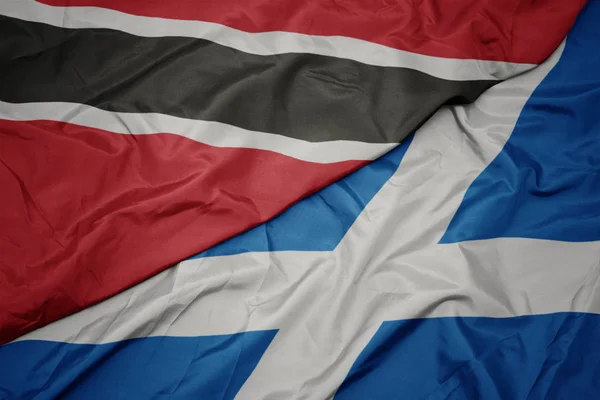 waving colorful flag of scotland and national flag of trinidad and tobago.