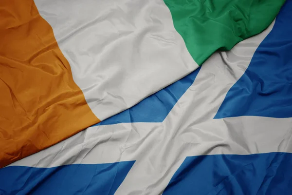 waving colorful flag of scotland and national flag of cote divoire.