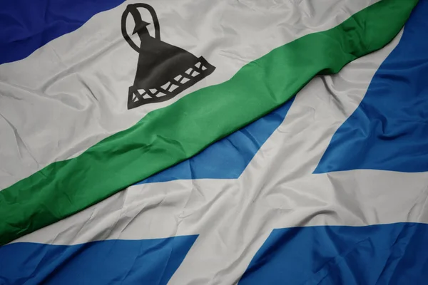 Acenando bandeira colorida da Escócia e bandeira nacional do lesotho . — Fotografia de Stock