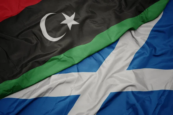 waving colorful flag of scotland and national flag of libya.