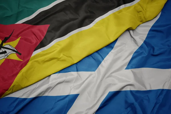 waving colorful flag of scotland and national flag of mozambique.