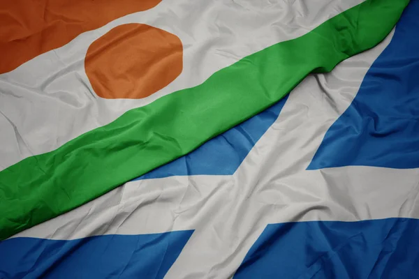 Acenando bandeira colorida da Escócia e bandeira nacional do Níger . — Fotografia de Stock
