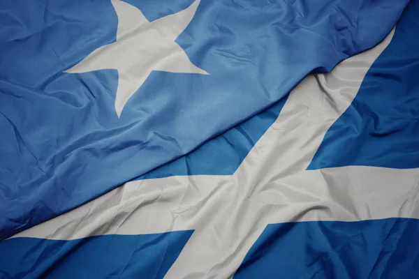 Acenando bandeira colorida da Escócia e bandeira nacional da Somália . — Fotografia de Stock