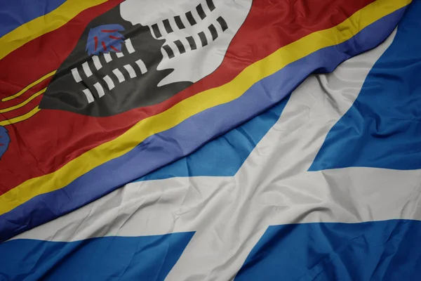 waving colorful flag of scotland and national flag of swaziland.
