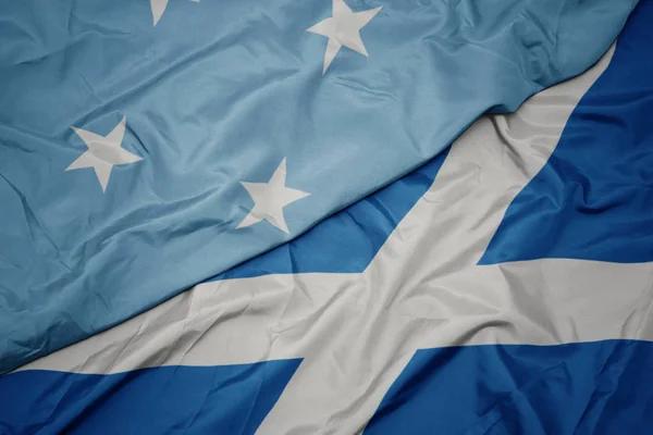 waving colorful flag of scotland and national flag of Federated States of Micronesia .