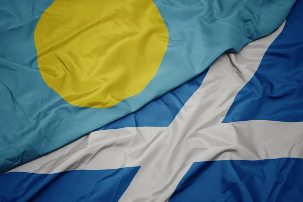 waving colorful flag of scotland and national flag of Palau .