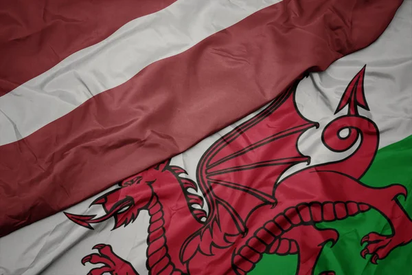 Waving colorful flag of wales and national flag of latvia. — Stock Photo, Image