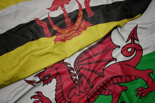 Machanie kolorową flagą Walii i flagą narodową Brunei. — Zdjęcie stockowe