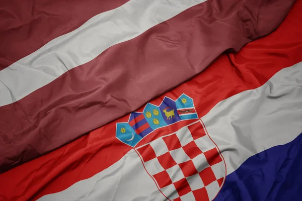 Махаючи барвистим прапором Хорватії та національним прапором Латвії . — стокове фото