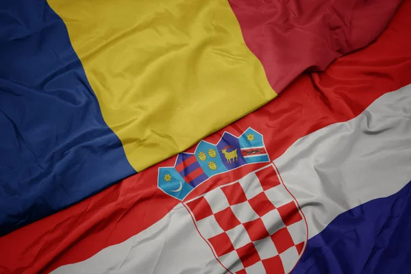 Mávání barevnou vlajkou Chorvatska a národní vlajkou Romie. — Stock fotografie