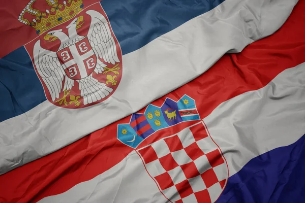 Agitant drapeau coloré de la croatie et drapeau national de la serbie . — Photo