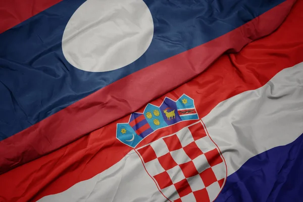 Ondeando colorida bandera de croacia y bandera nacional de laos . — Foto de Stock