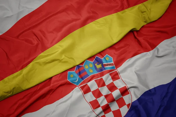 Agitant drapeau coloré de la croatie et drapeau national de l'Ossétie du Sud — Photo