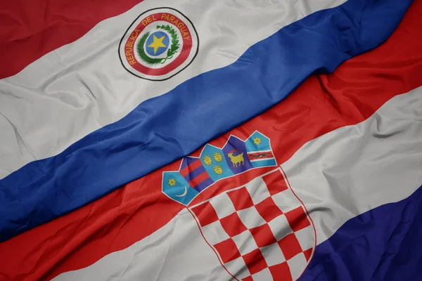 Ondeando colorida bandera de croacia y bandera nacional de paraguay . —  Fotos de Stock