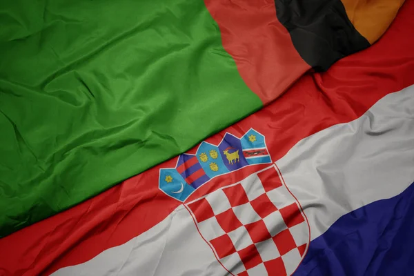 Mávání barevnou vlajkou Chorvatska a národní vlajky zambia. — Stock fotografie