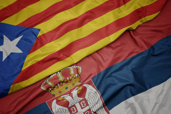 waving colorful flag of serbia and national flag of catalonia.
