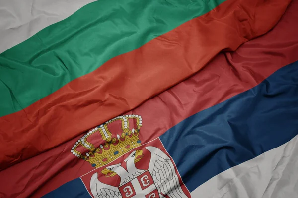 Acenando bandeira colorida da Sérvia e bandeira nacional da Bulgária . — Fotografia de Stock