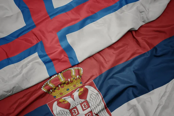 waving colorful flag of serbia and national flag of faroe islands.