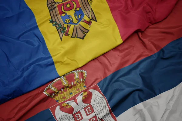Acenando bandeira colorida da Sérvia e bandeira nacional da Moldávia . — Fotografia de Stock
