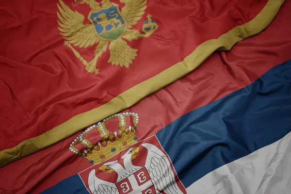 Agitant drapeau coloré de la serbie et drapeau national de montenegro . — Photo
