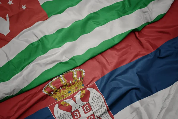 waving colorful flag of serbia and national flag of abkhazia.