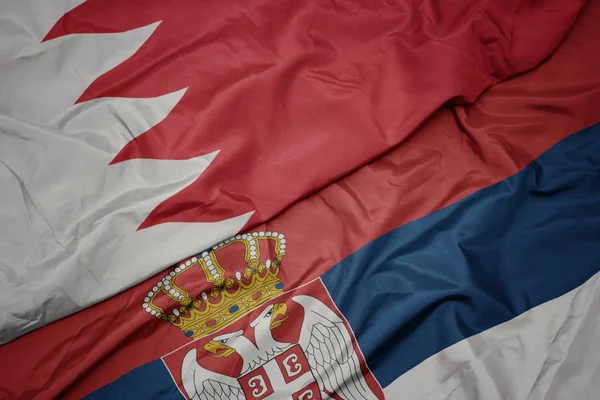 waving colorful flag of serbia and national flag of bahrain.