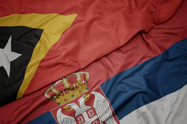 Sırbistanın renkli bayrağı ve Doğu Timor 'un ulusal bayrağı sallanıyor.. — Stok fotoğraf