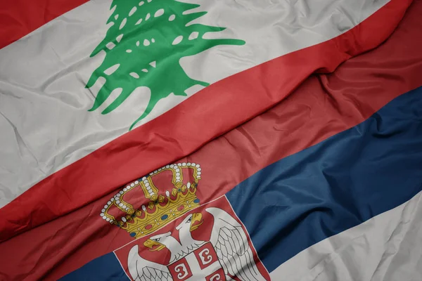 waving colorful flag of serbia and national flag of lebanon.