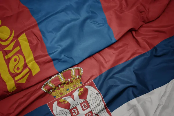 Agitant drapeau coloré de la serbie et drapeau national de la mongolie . — Photo