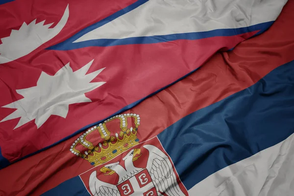 waving colorful flag of serbia and national flag of nepal.